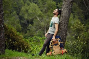 Hiker resting leaning against a tree on the little wood hill