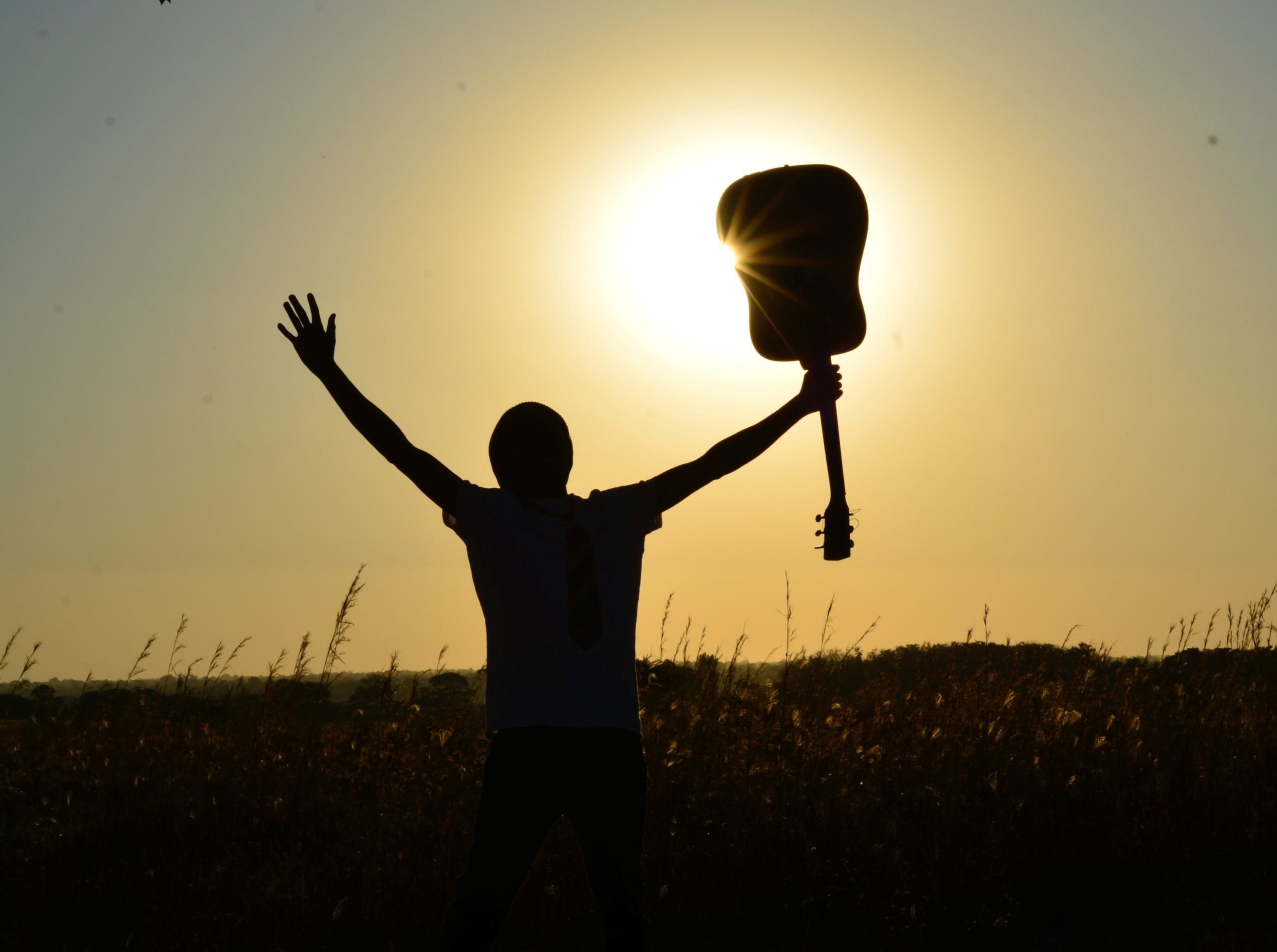 Man holding a guitar celebrating his recovery through music therapy.